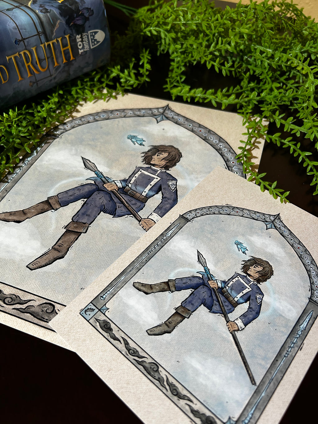 Two different sized prints  featuring a character in a fantasy setting with greenery in the background